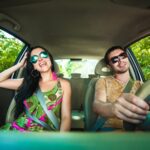 Young Couple Driving Along Country Road.