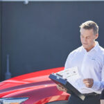 Female car owner and male service technician standing in front of Mazda car outside service center